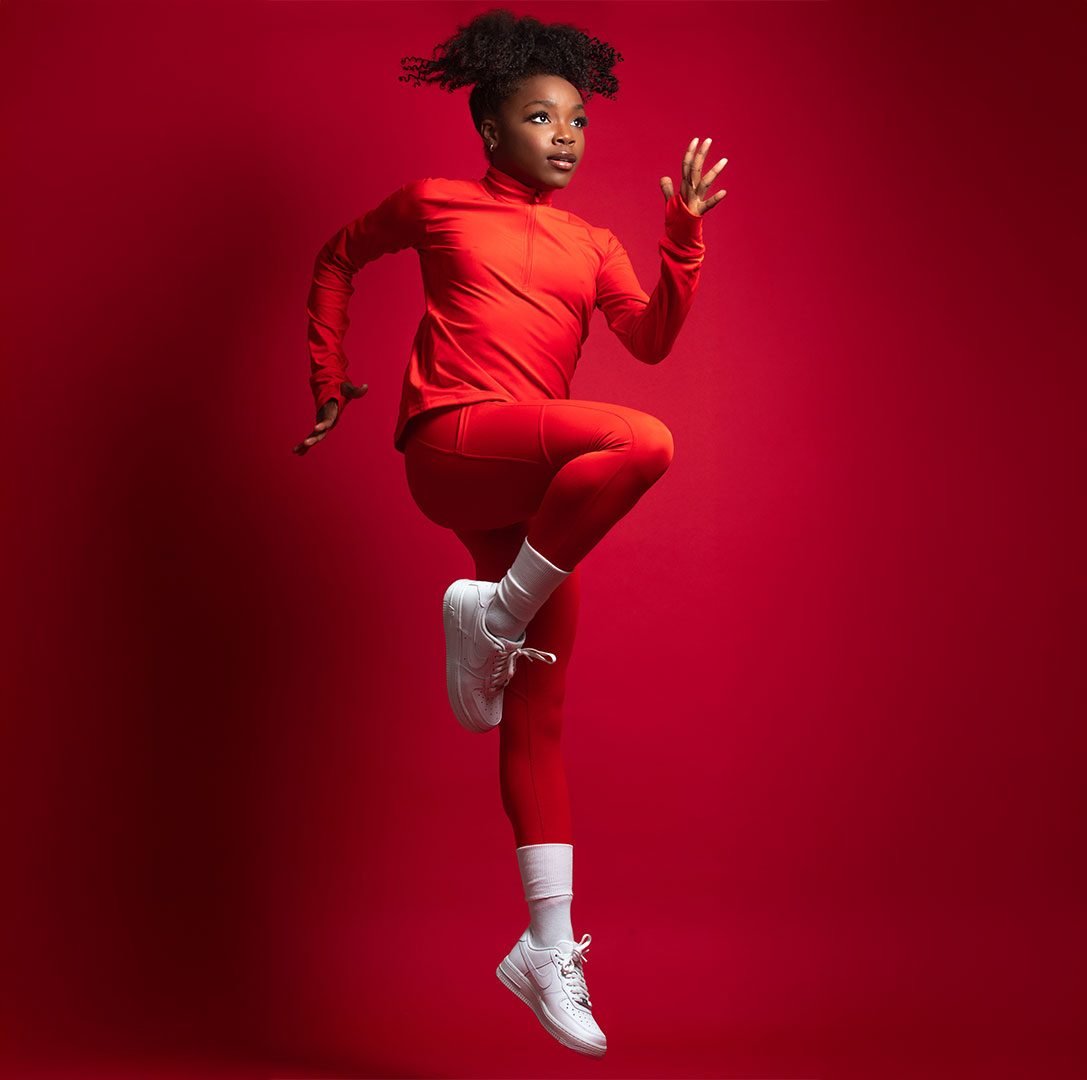 Dancer mid-leap in red against a red backdrop